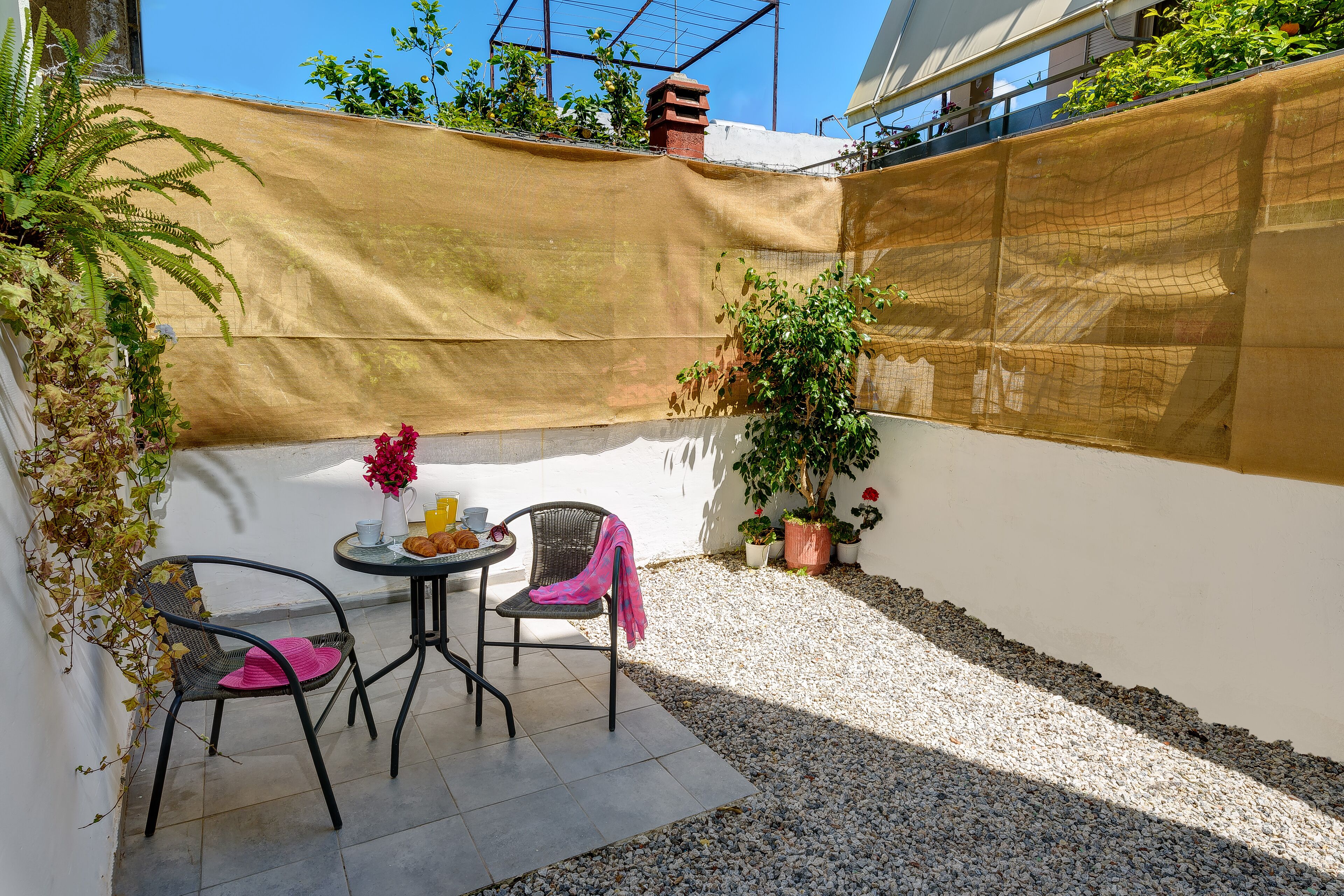 A small patio area with two chairs, a table, and a potted plant.