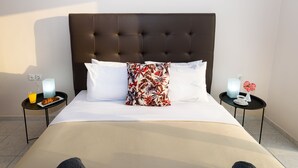 A hotel room with a large bed, two bedside tables, and a nightstand with a lamp. - Room25 (Chania)