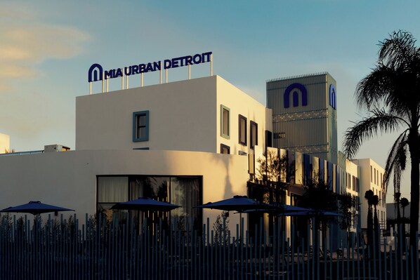Un edificio moderno con un cartel que dice "MIA URBAN DETROIT" y una estructura alta con un logotipo similar.