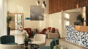 Una hall moderna con una reception, area salotto e un soffitto con lampade pendenti.