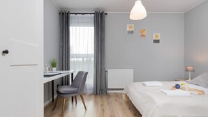 A modern bedroom with a bed, bedside table, and a desk with a chair.