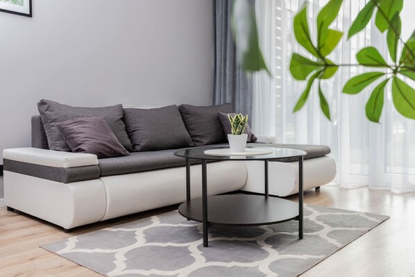 A modern living room with a grey sofa, a round coffee table, and a potted plant.