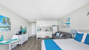 A modern hotel room with a large bed, a dining area with a glass table, a kitchen area, and artwork on the walls. - "Bahama" Studio w/ FREE Parking & Full Kitchen (Honolulu)