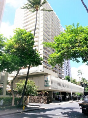 A multi-story hotel with a modern design, featuring balconies and a stone facade.