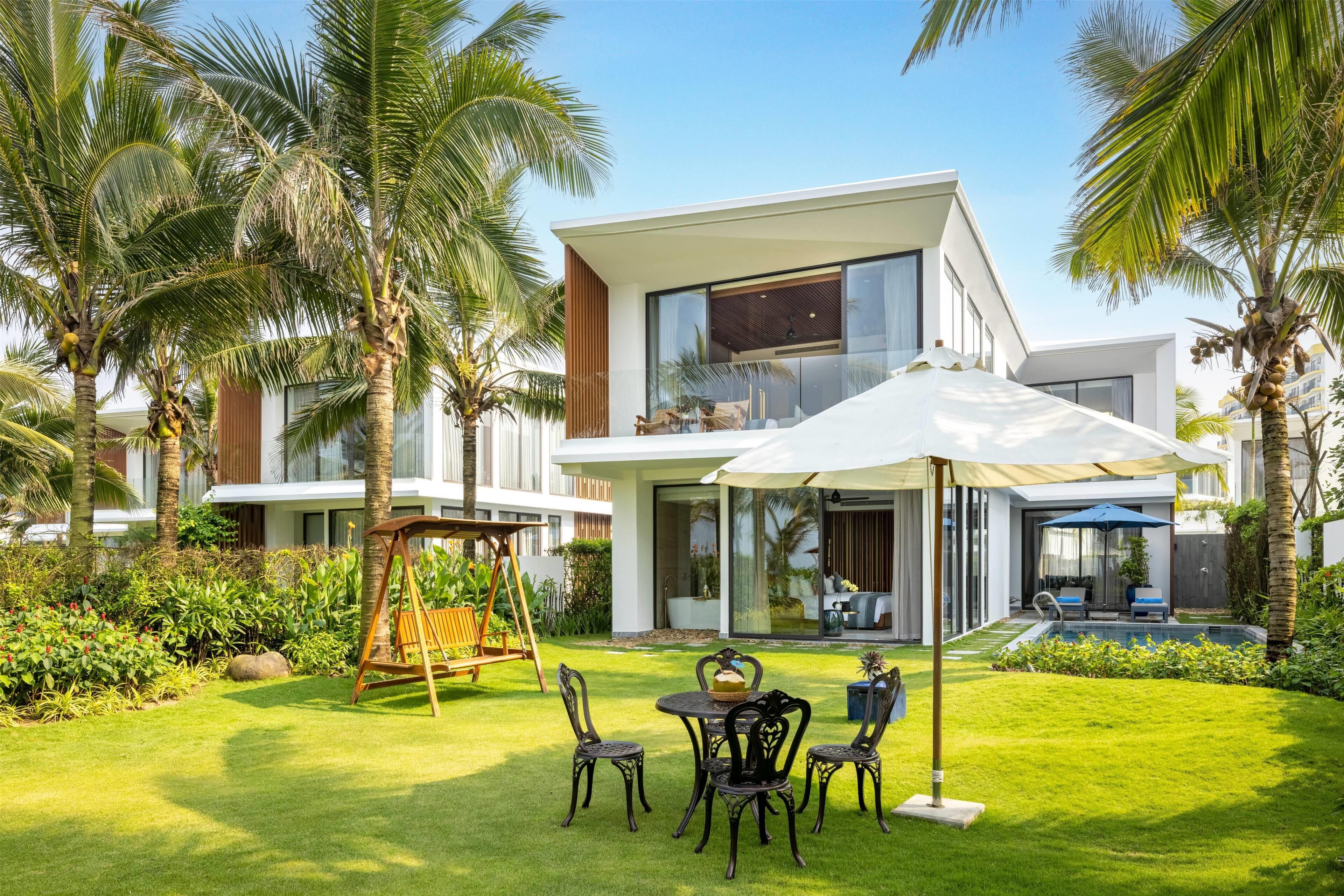 A modern house with a patio, a swing set, and a pool.