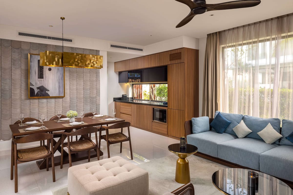 A modern living room with a dining area, a sofa, and a kitchen in the background.