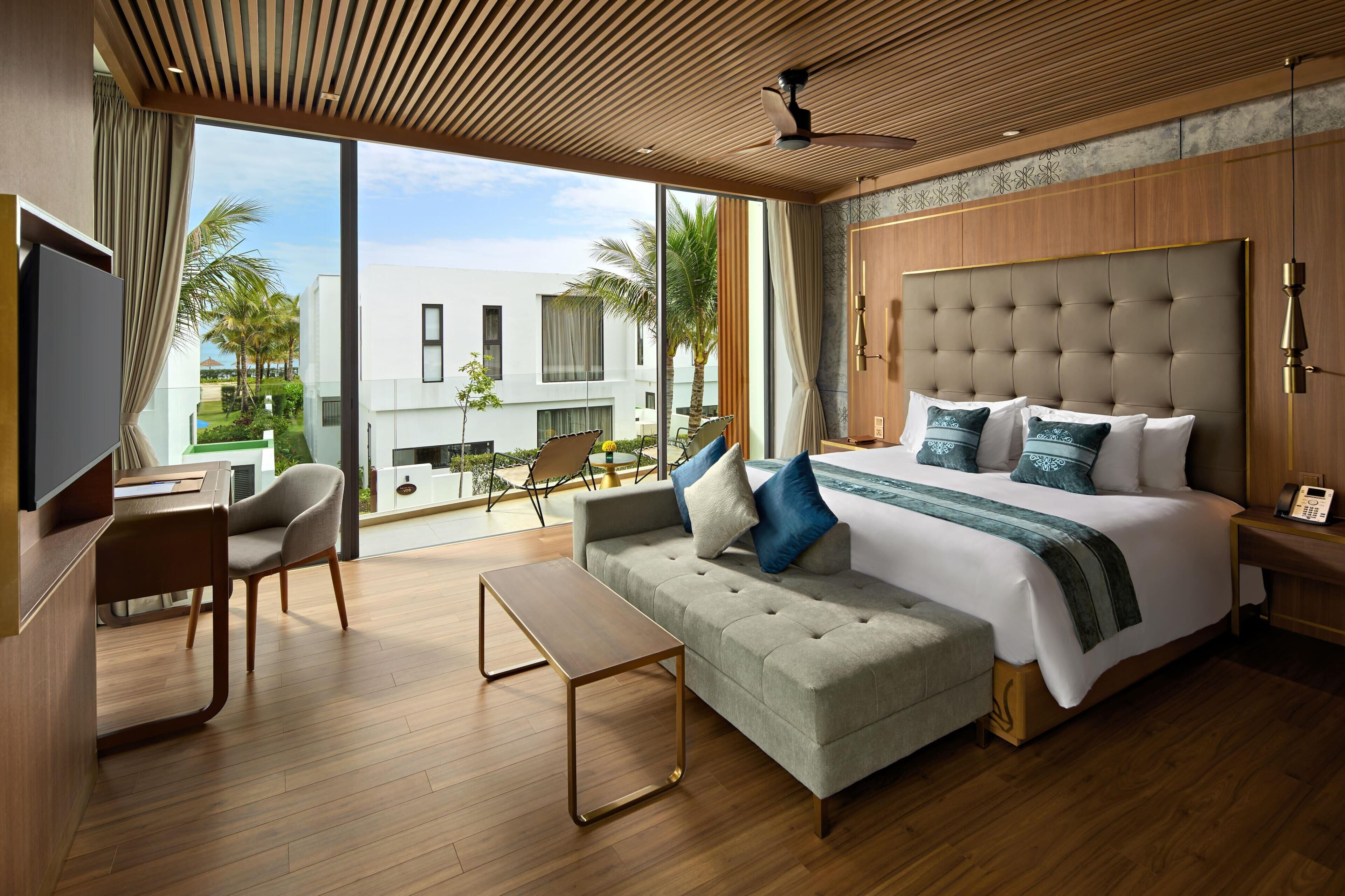 Een moderne hotelkamer met een groot bed, een bank, een bureau en uitzicht op de omgeving.