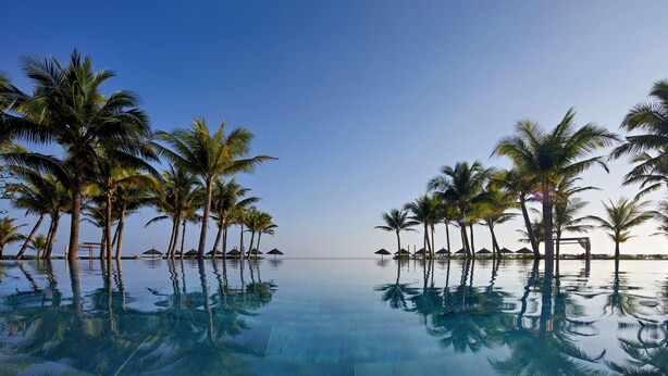 A pool with clear water reflecting palm trees and a clear sky. - Wyndham Royal Beachfront Resort & Spa Hoi An Danang (Da Nang)