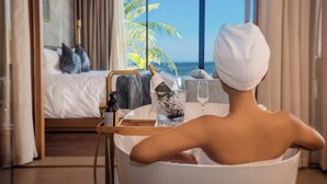 Une chambre avec un lit, une baignoire et vue sur l’océan.