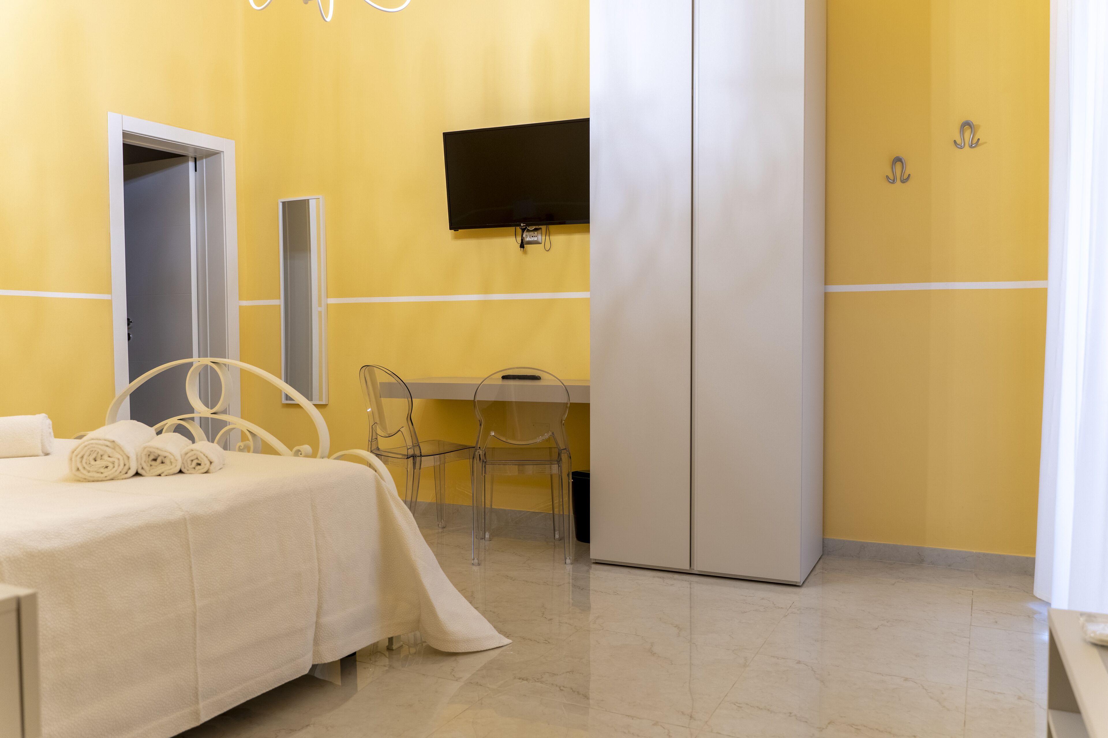 A hotel room with a bed, a desk, a chair, a TV, and a wardrobe.