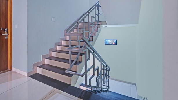Una escalera moderna con barandillas de metal, una puerta de madera y un pequeño cuadro enmarcado en la pared.