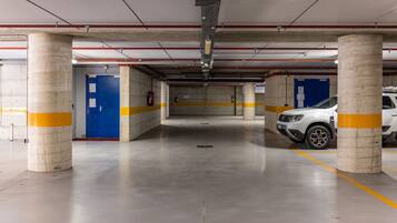 A multi-level parking garage with concrete pillars, yellow safety lines, and a white car parked.