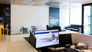Un espacio de oficina moderno con un escritorio, un teléfono y una pared divisoria de vidrio.