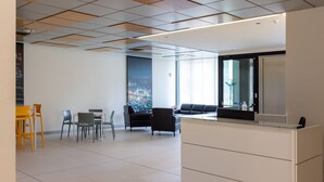 Un espacio de oficina moderno con mostrador de recepción, área de estar y un amplio ventanal con vista a la ciudad.