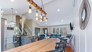 Une cuisine spacieuse avec un grand îlot central, un coin repas avec une table en bois et un salon doté d’un canapé et d’un téléviseur.