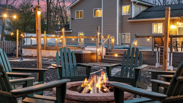 Un espace extérieur aménagé avec des chaises Adirondack, un foyer et des guirlandes lumineuses.