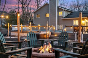A patio area with Adirondack chairs, a fire pit, and string lights.