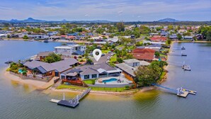 Vista aérea de una zona residencial costera con casas, un muelle y una piscina.
