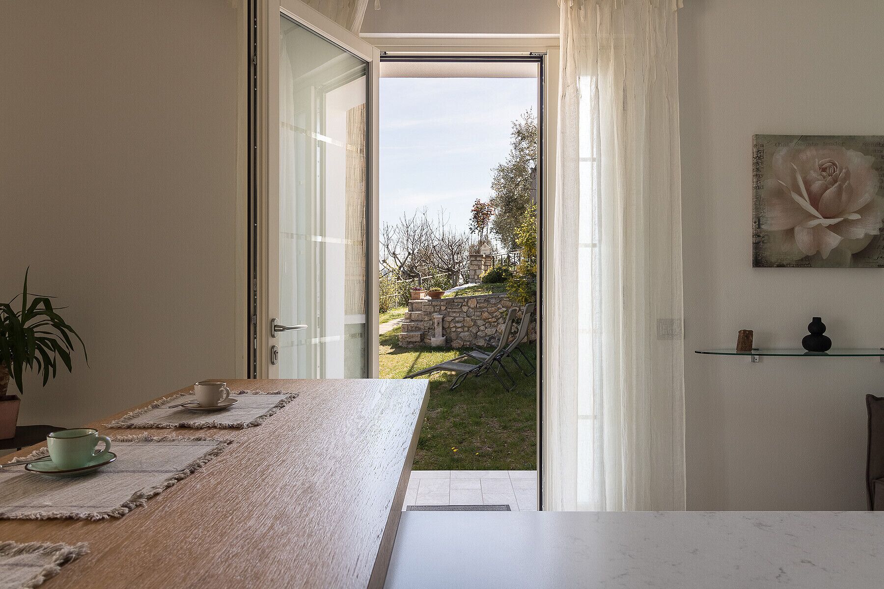 Ein Zimmer mit Blick auf einen Garten, durch einen geöffneten Durchgang.