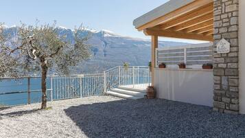 Eine Terrasse mit Steinmauer, einer Holzpergola und einem Schild, das eine Ferienwohnung kennzeichnet.
