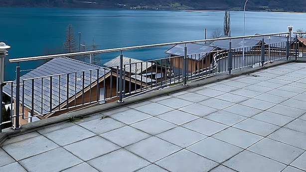 Een terras op het dak met uitzicht op een meer en bergen.