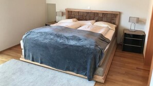 Een slaapkamer met een bed, nachtkastjes en een houten plafond.