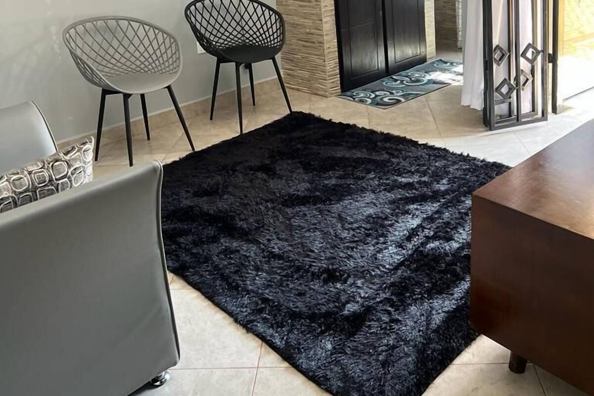 Une cuisine moderne avec des meubles de couleur sombre, un tapis noir et un coin repas avec deux chaises.