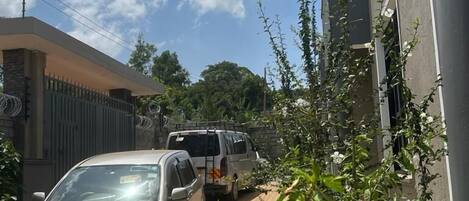 A residential area with a paved driveway, a parked silver car, and a white van.