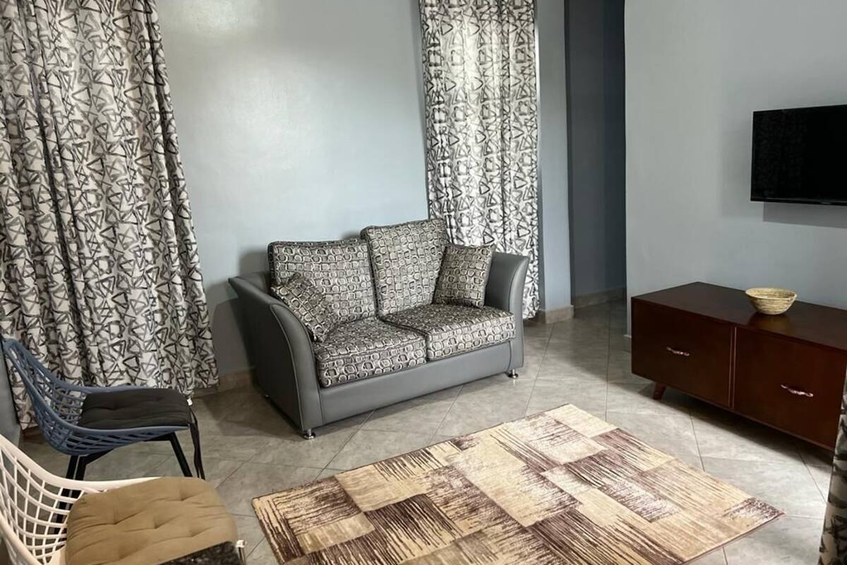Un salon avec un canapé, une table basse, un téléviseur, un meuble et des rideaux à motifs.