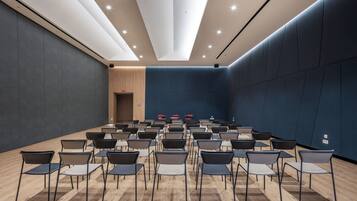 A conference room with rows of chairs and tables, a wooden door, and a dark blue wall.