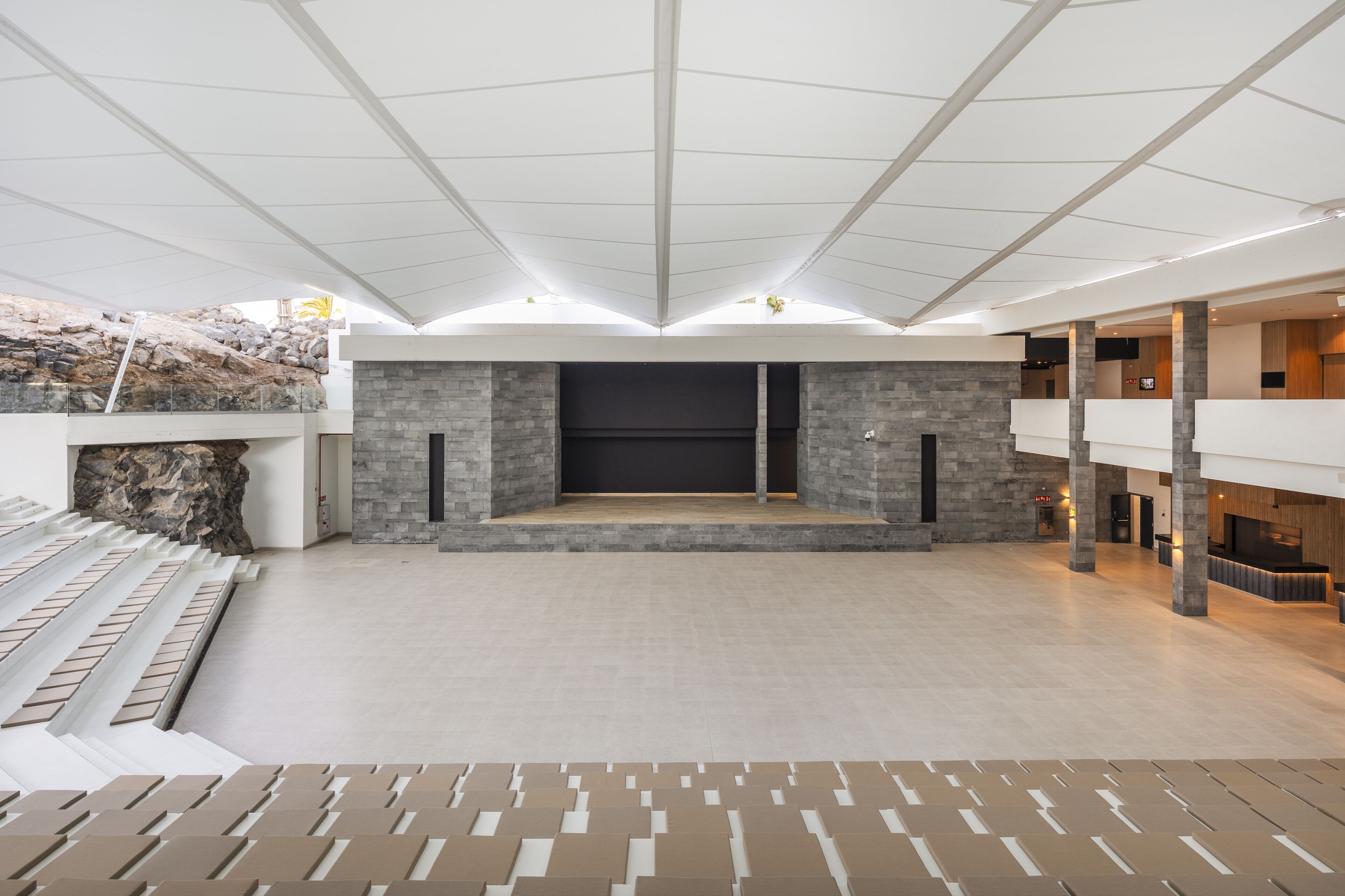 A spacious lobby with a stone fireplace, a reception desk, and a high ceiling with a grid pattern.