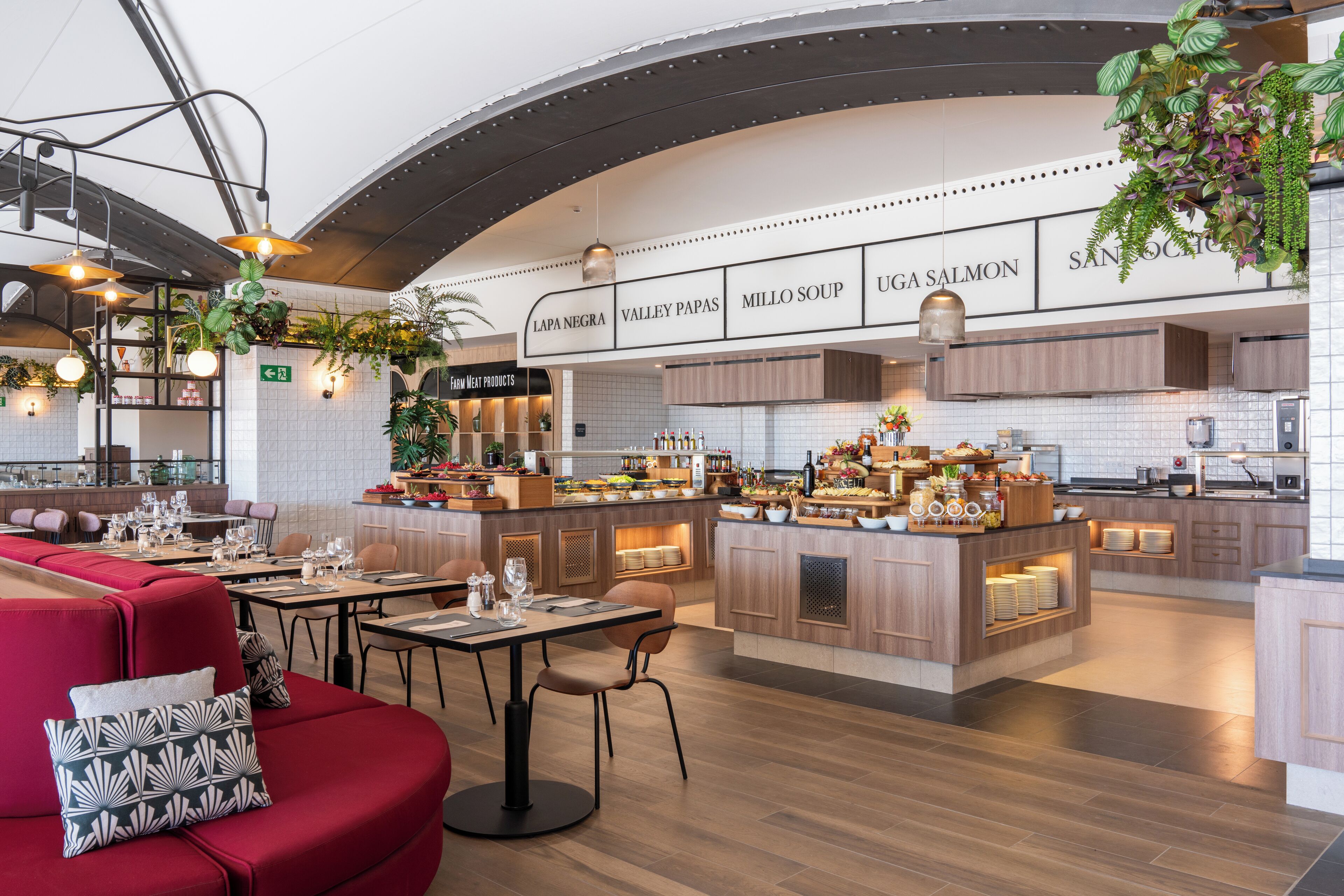 A modern restaurant with a central island, seating area, and a kitchen in the background.