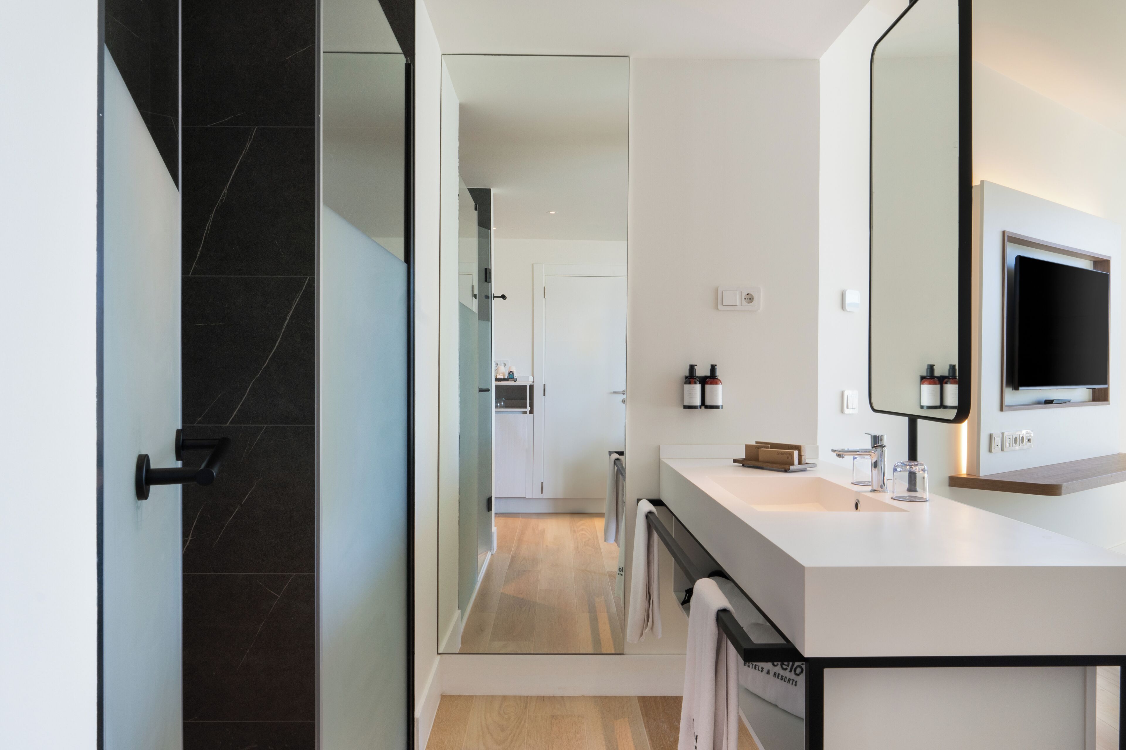 A modern bathroom with a large mirror, a sink, and a shower area.