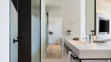 A modern bathroom with a large mirror, a sink, and a shower area.