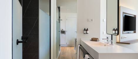 A modern bathroom with a large mirror, a sink, and a shower area.