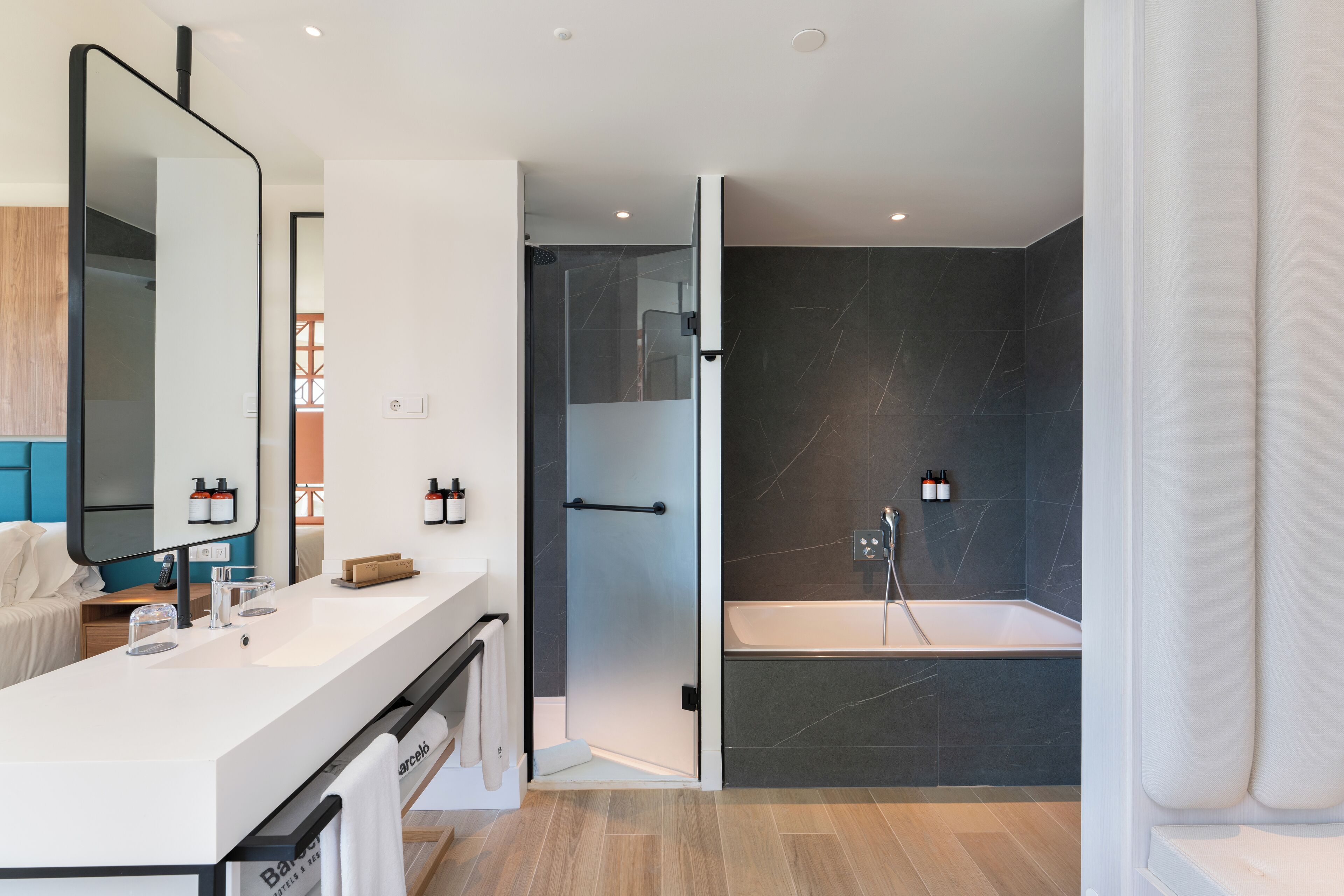 A modern bathroom with a large mirror, a sink, and a bathtub.
