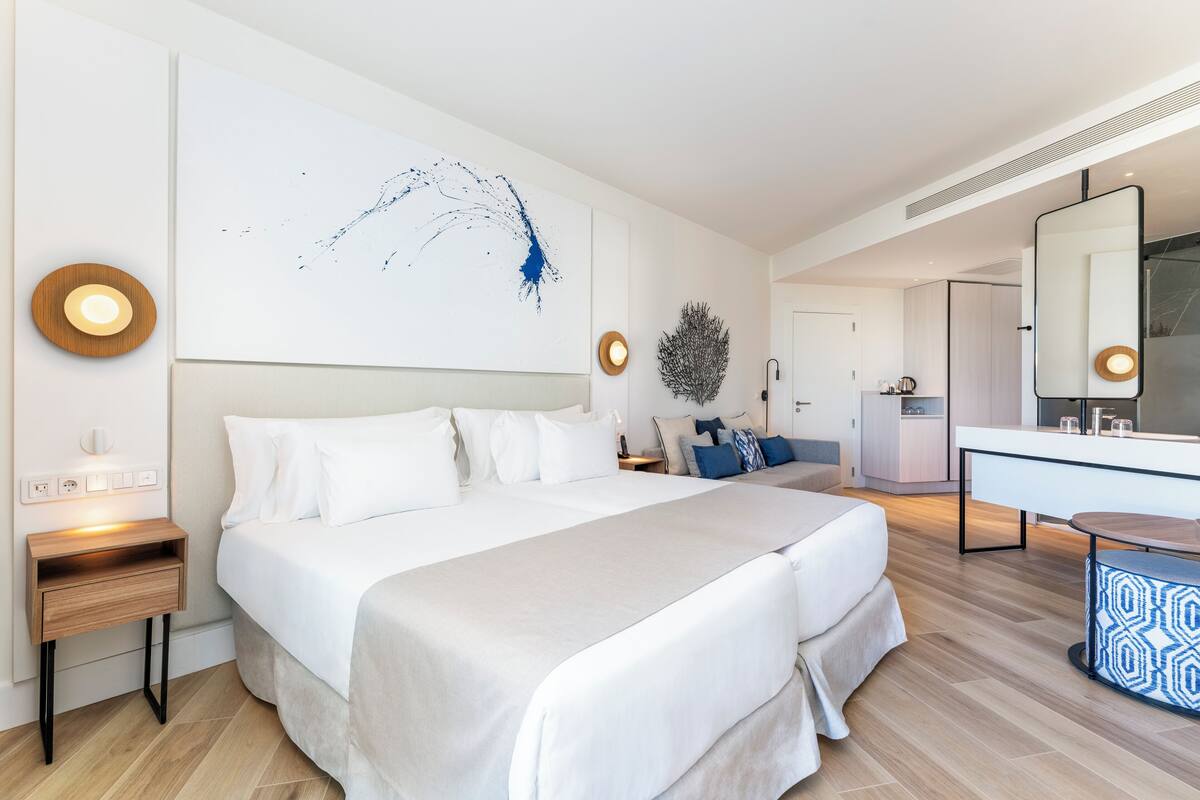 Ein modernes Hotelzimmer mit einem großen Bett, Nachttischen, einem Schreibtisch, einem Spiegel und einem Wandbild.