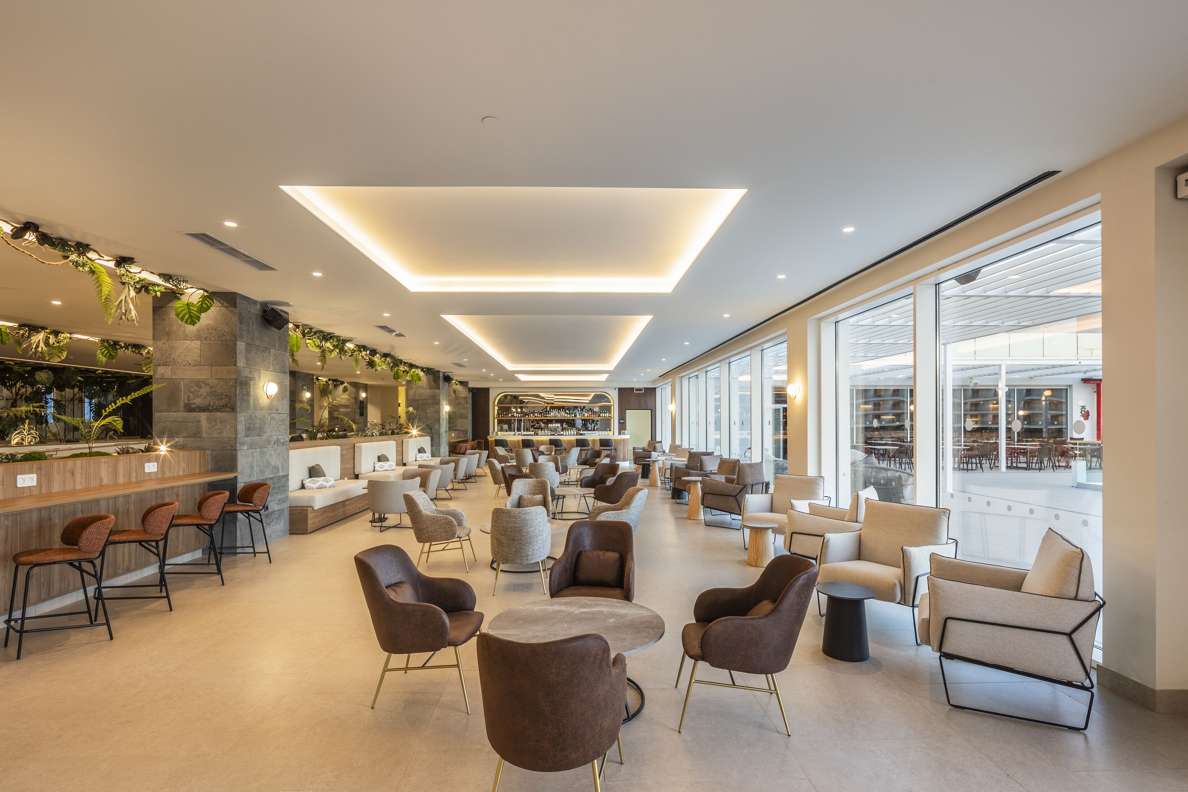 A spacious lobby with modern seating, a bar area, and large windows offering views of the interior.