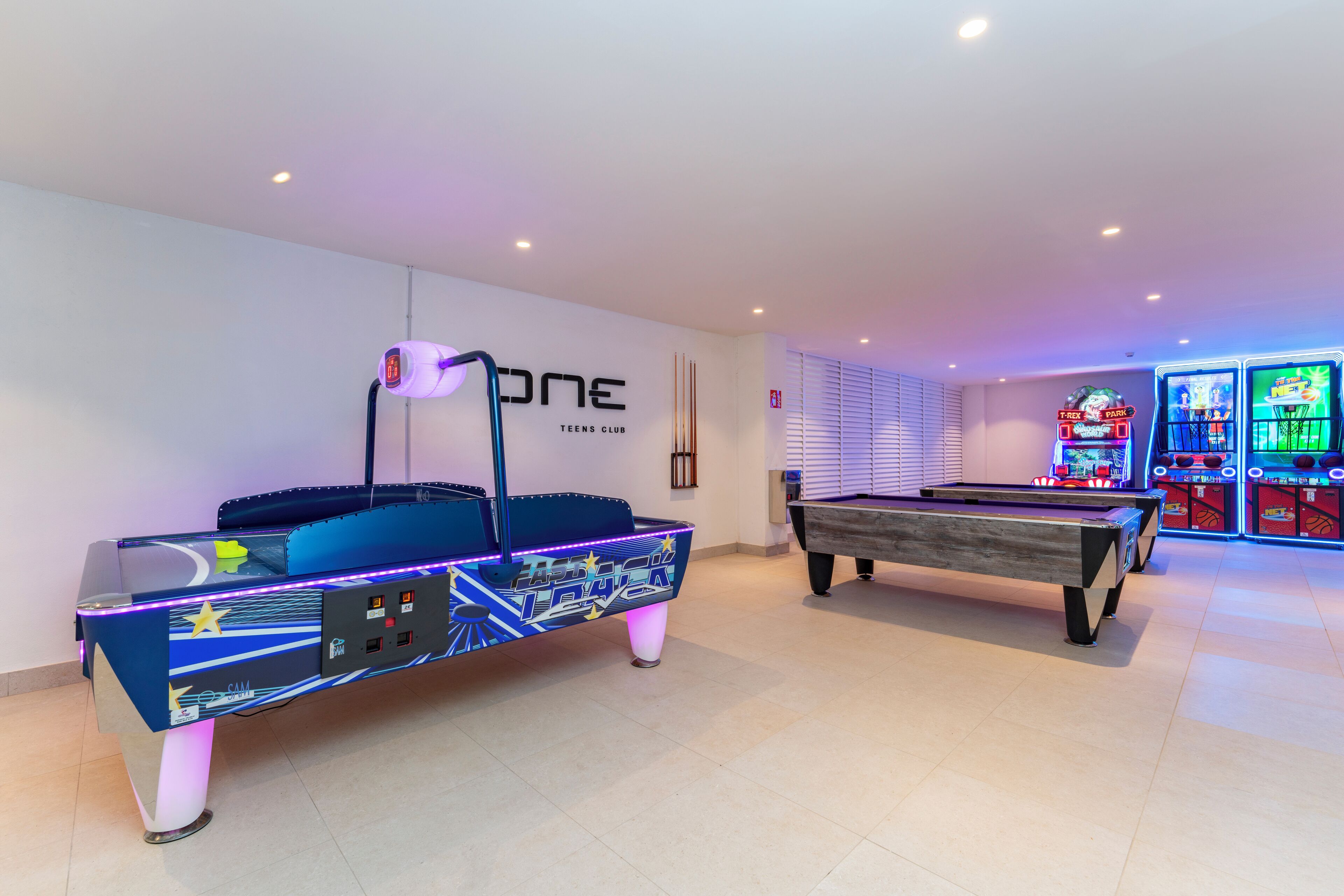 A pool table and a pool table with a neon design in a room with arcade games.