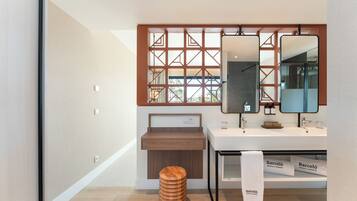 Un baño moderno con un taburete de madera, un espejo grande y una ventana con diseño geométrico.
