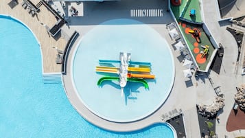 An aerial view of a pool area with a circular water feature, lounge chairs, and a small play area.
