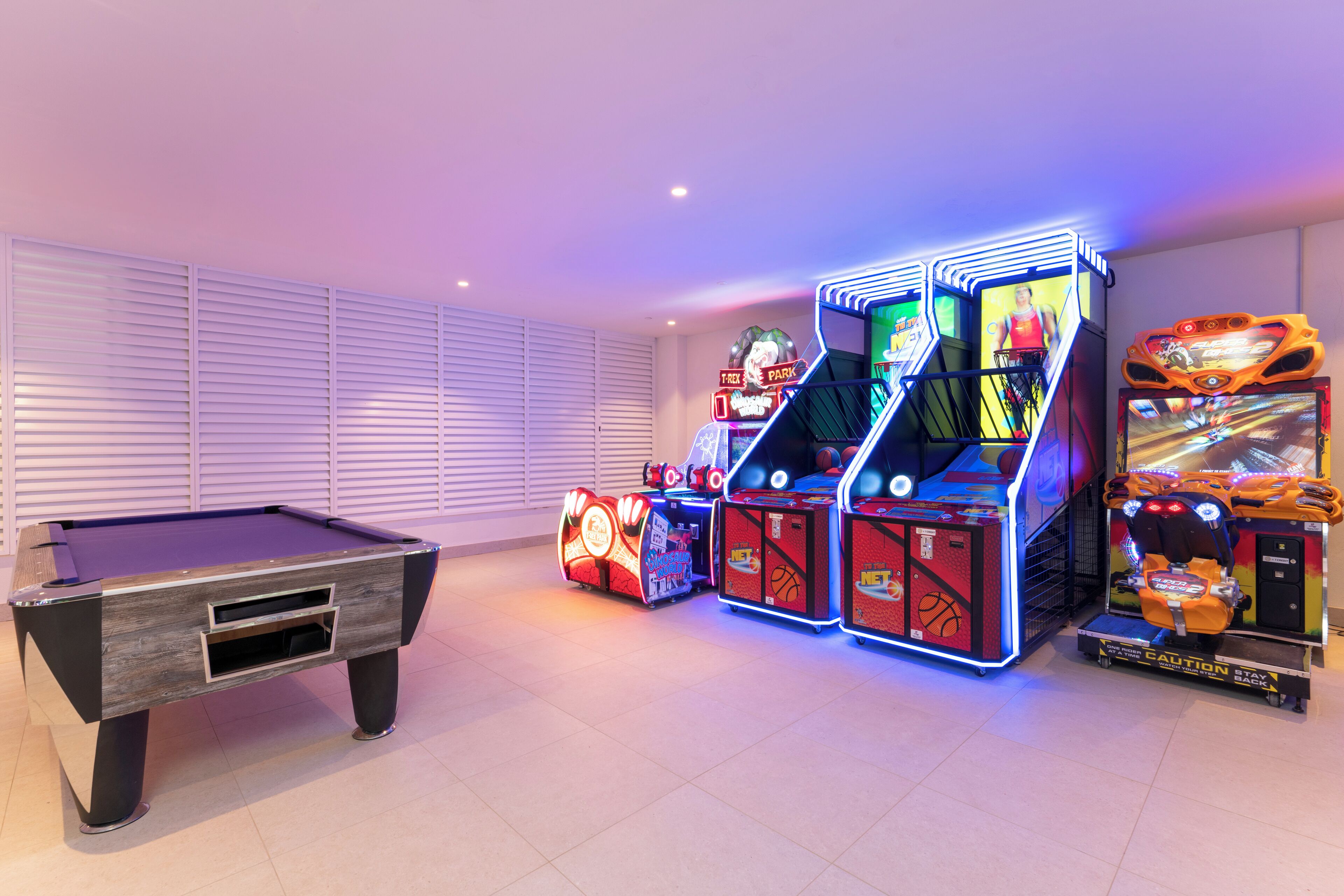 A pool table with arcade machines and a basketball game.
