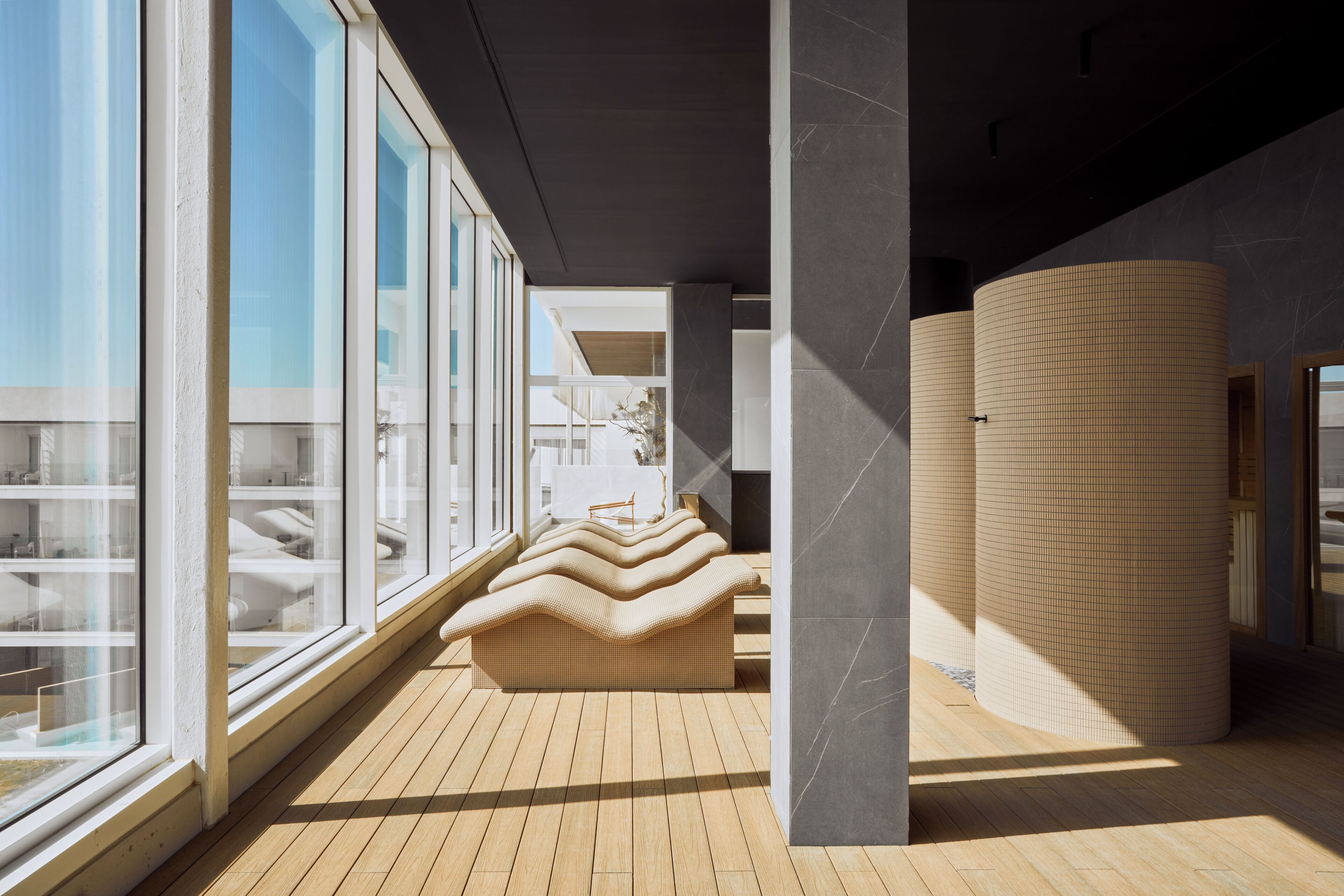 Un intérieur moderne avec de grandes fenêtres, un plancher en bois et un espace salon doté d’un design ondulé original.