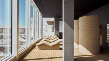 Un intérieur moderne avec de grandes fenêtres, un plancher en bois et un espace salon doté d’un design ondulé original.