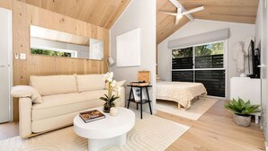 Une chambre à coucher moderne avec un lit, une table de chevet, une fenêtre et un ventilateur de plafond.