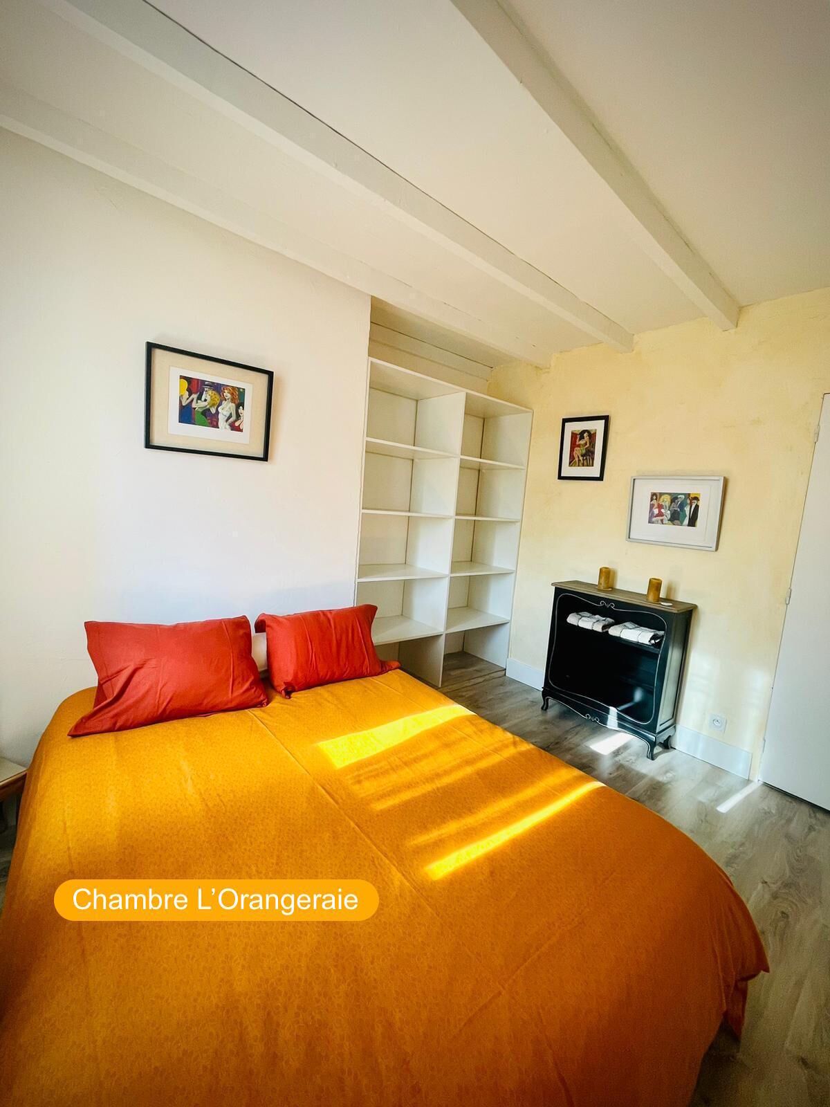 A bedroom with a large bed, a wardrobe, and a small table with a lamp.