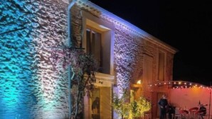 Un edificio con fachada de piedra y una zona junto a la piscina con velas y luces colgantes.