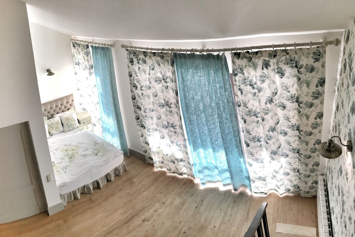 A bedroom with two beds, a wooden floor, and a staircase.