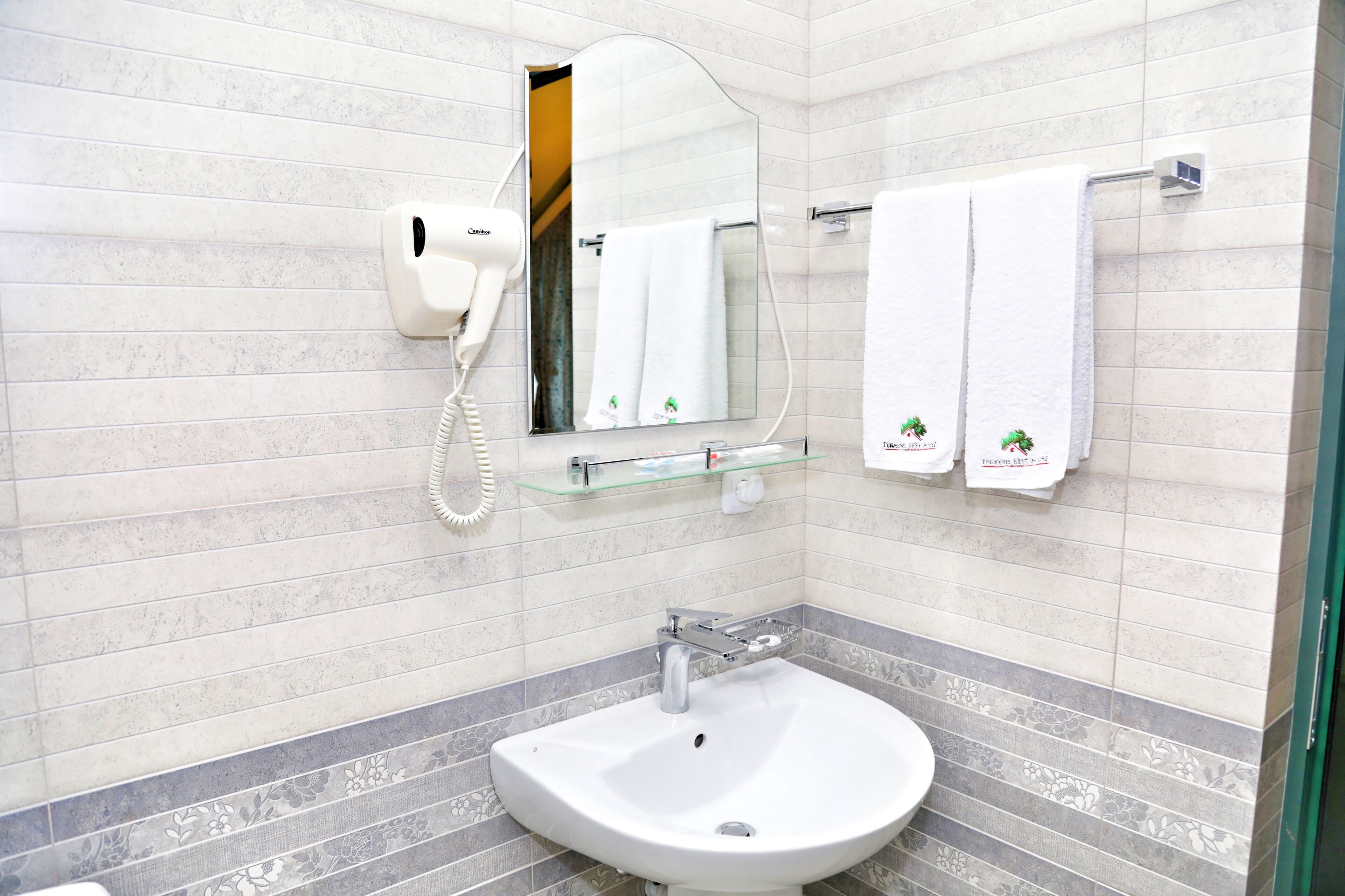 A bathroom with a white sink, a mirror, and a towel rack with two white towels.
