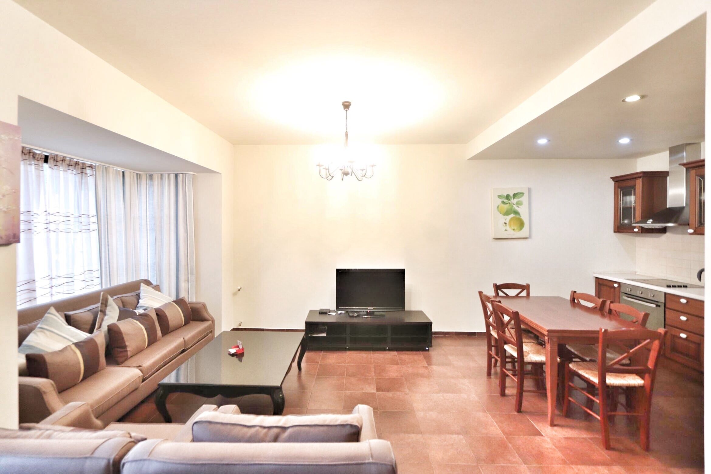 A living room with a sofa, TV, and dining area with chairs and a table.